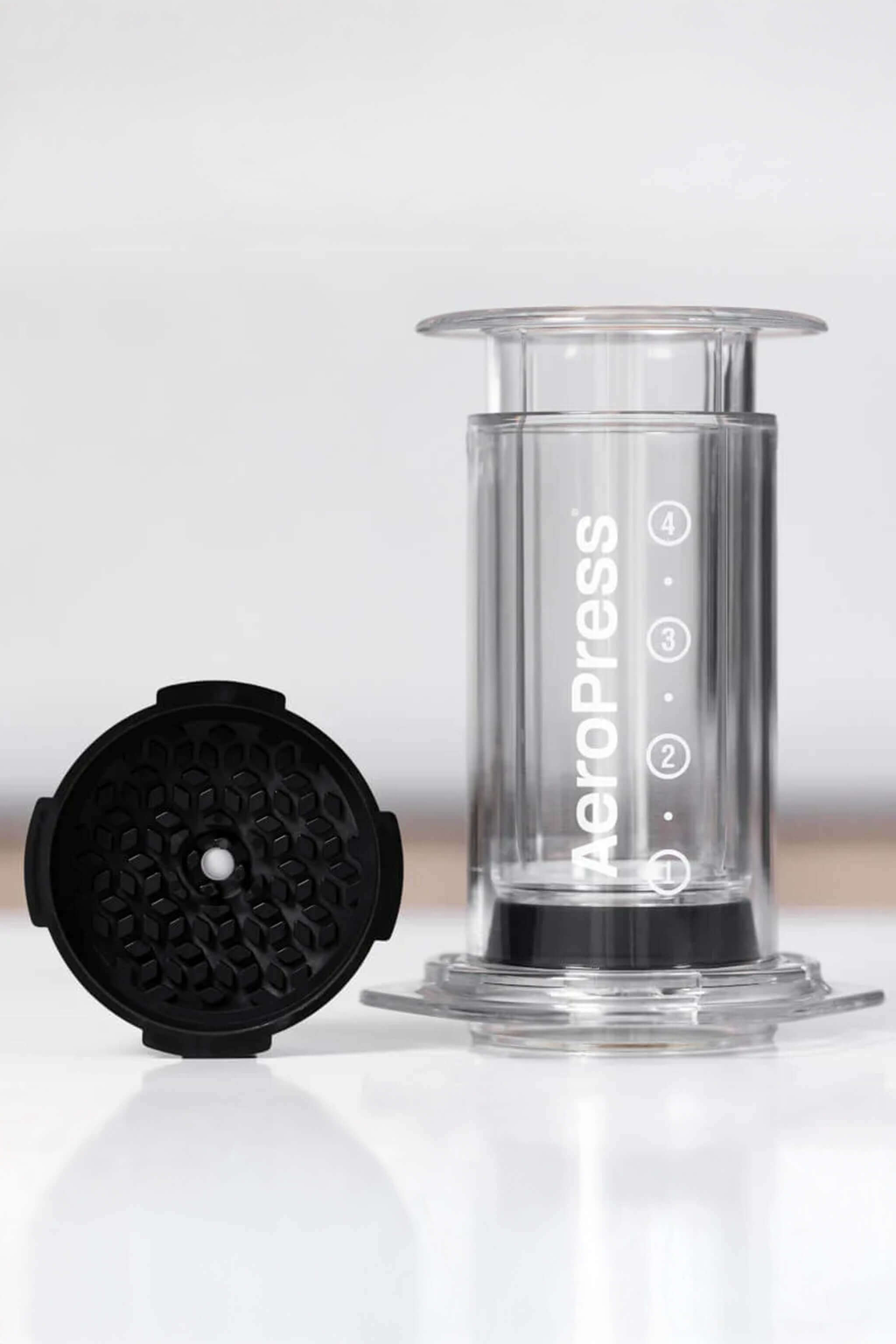 Aeropress coffee maker with black lid on a white background