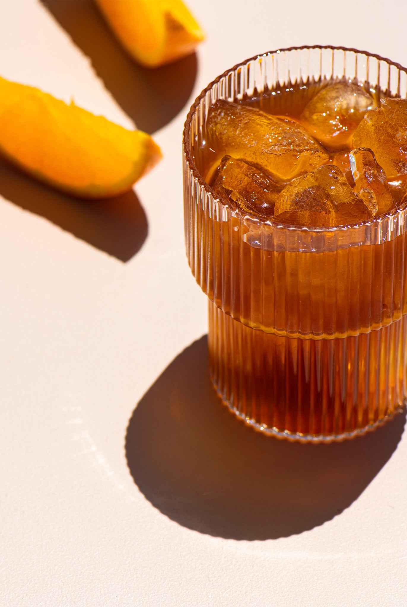 Tumbler of Cold Brew Coffee with ice with orange slices in the background